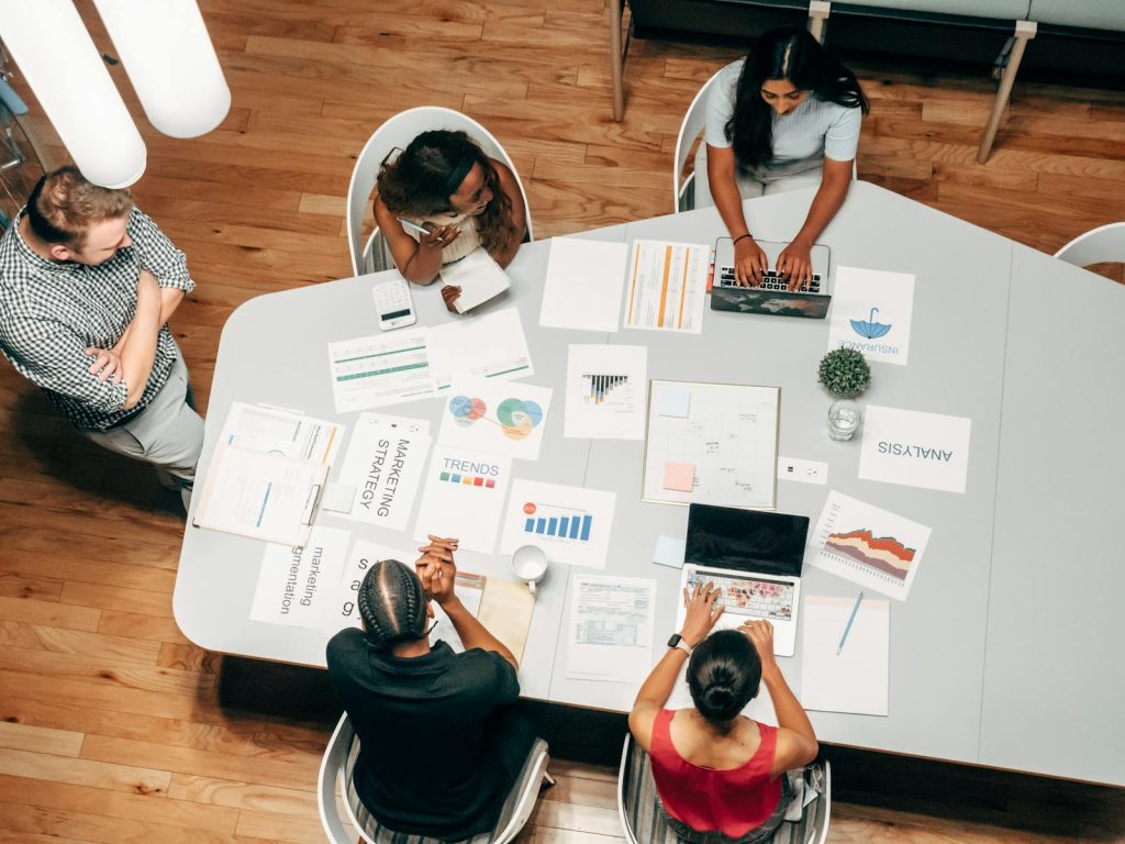 Un groupe diversifié travaillant sur des stratégies de marketing avec des graphiques et des ordinateurs portables dans un environnement de bureau.