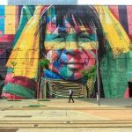 Une immense fresque murale colorée représentant le visage expressif d'une personne dans l'esprit artistique de Holbox.